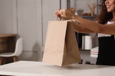 Worker with paper bag at counter in cafe, closeup. Space for text
