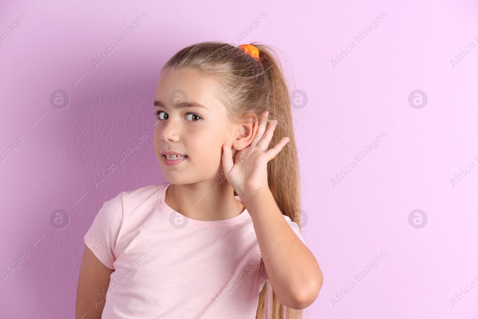 Photo of Cute little girl with hearing problem on color background