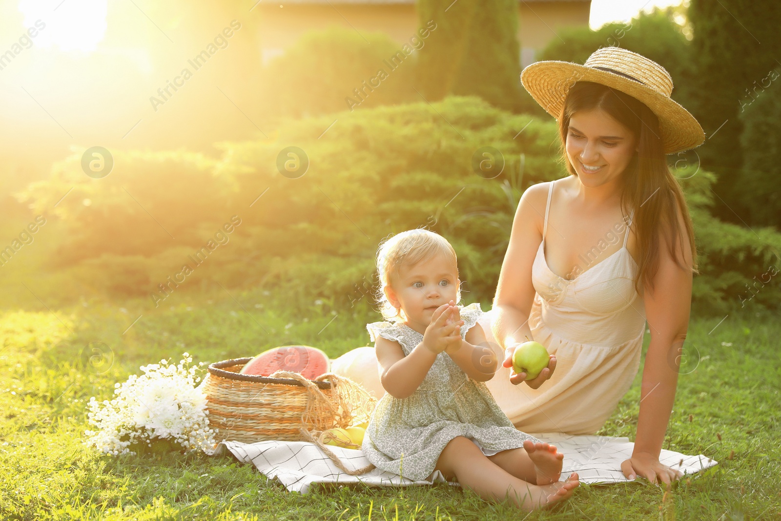 Photo of Mother with her baby daughter having picnic in garden on sunny day