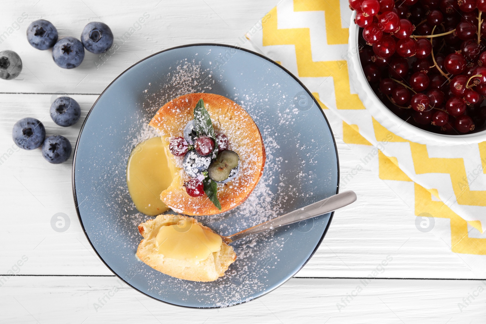 Photo of Tasty vanilla fondant with white chocolate and berries on light wooden table, flat lay