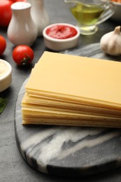 Photo of Cooking lasagna. Board with pasta sheets on dark table