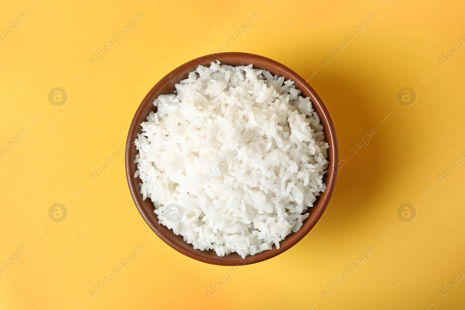 Photo of Bowl of boiled rice on color background, top view