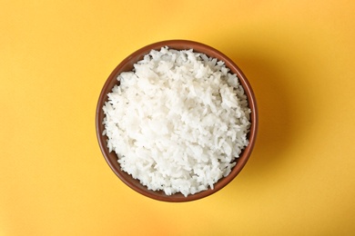 Photo of Bowl of boiled rice on color background, top view