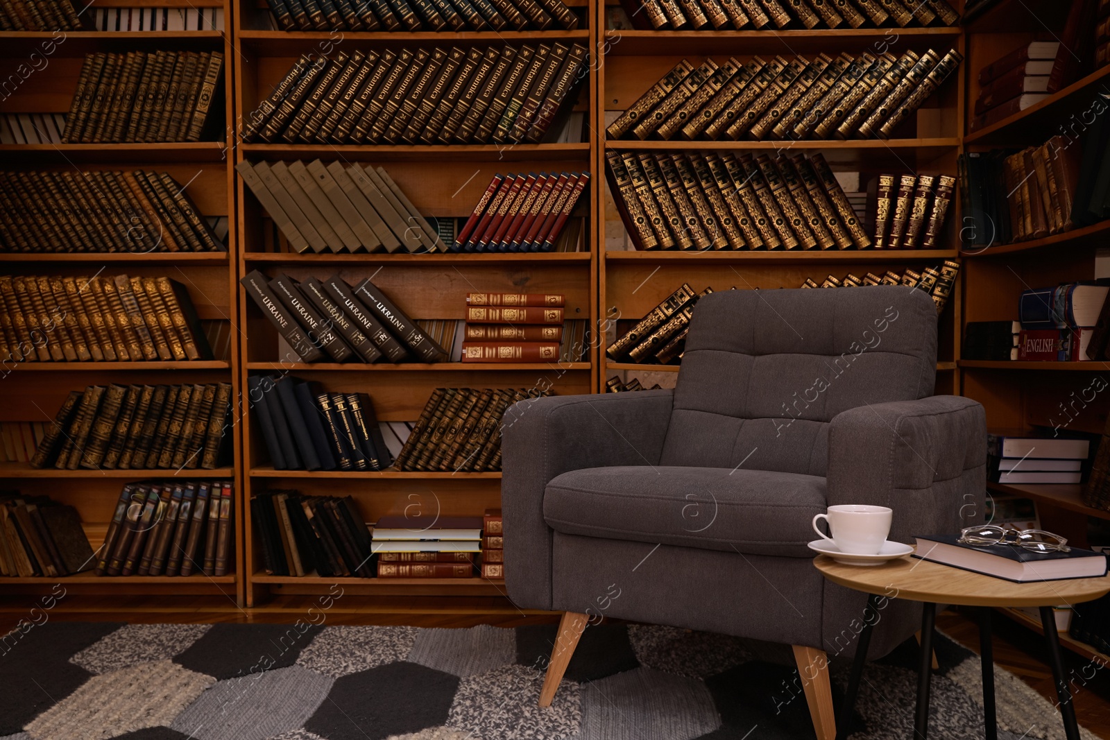 Photo of Cozy home library interior with comfortable armchair and collection of vintage books on shelves