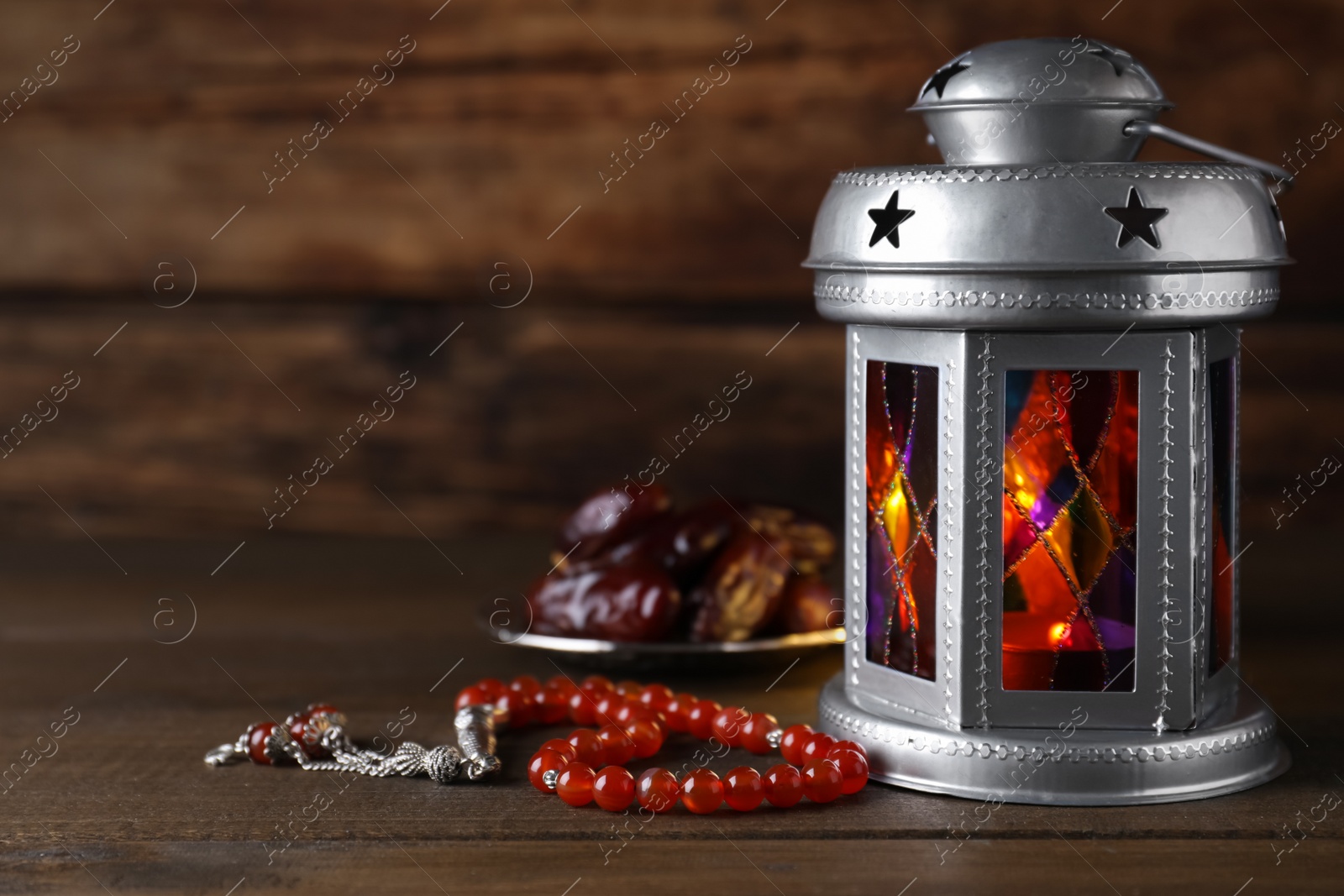 Photo of Arabic lantern and misbaha on wooden table. Space for text