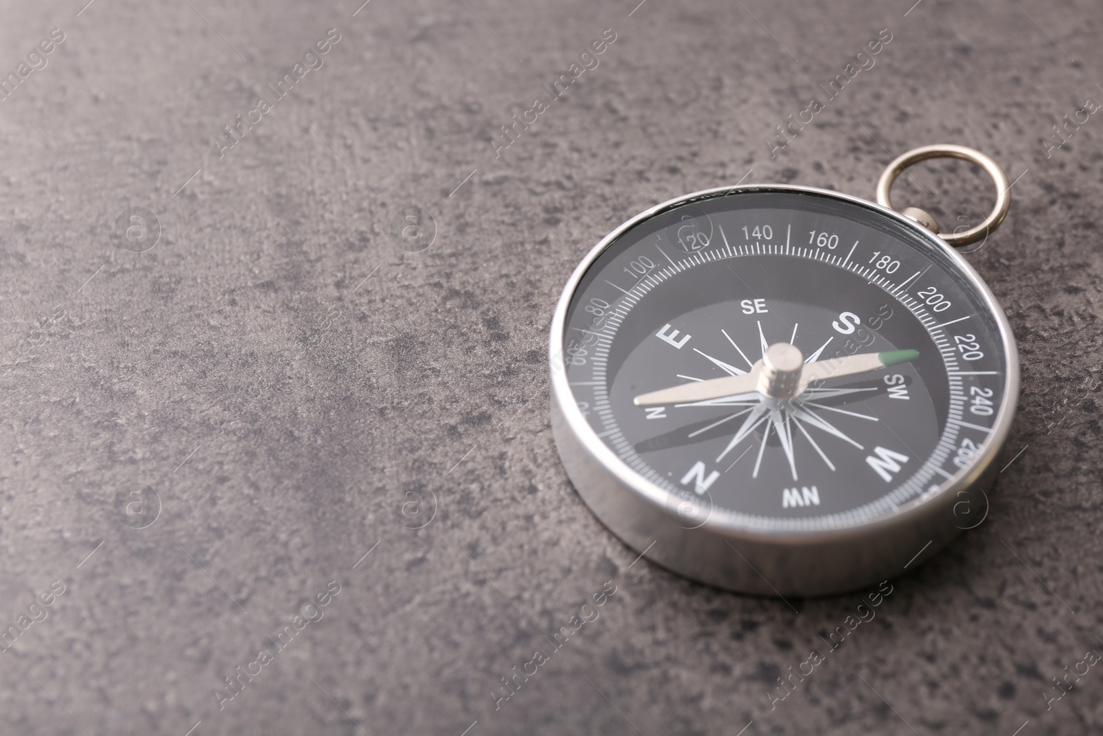 Photo of One compass on grey table, space for text. Tourist equipment