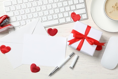 Photo of Flat lay composition with blank card on white wooden table, space for text. Valentine's Day celebration