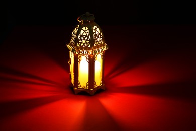 Photo of Decorative Arabic lantern on table against dark background. Space for text