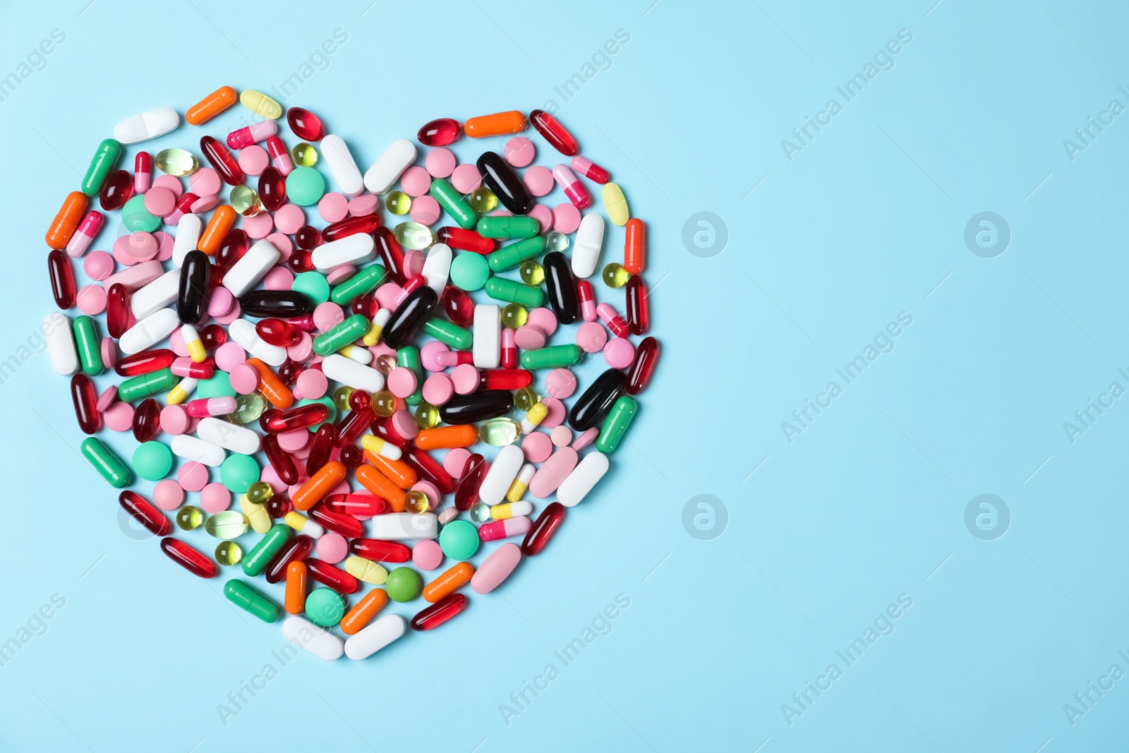 Photo of Heart made of pills on color background, top view with space for text. Cardiology concept