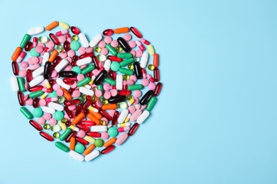 Heart made of pills on color background, top view with space for text. Cardiology concept