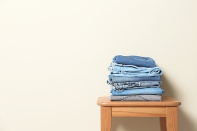 Photo of Stack of different jeans on table against light background. Space for text