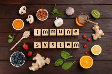 Cubes with phrase Immune System and fresh products on wooden table, flat lay