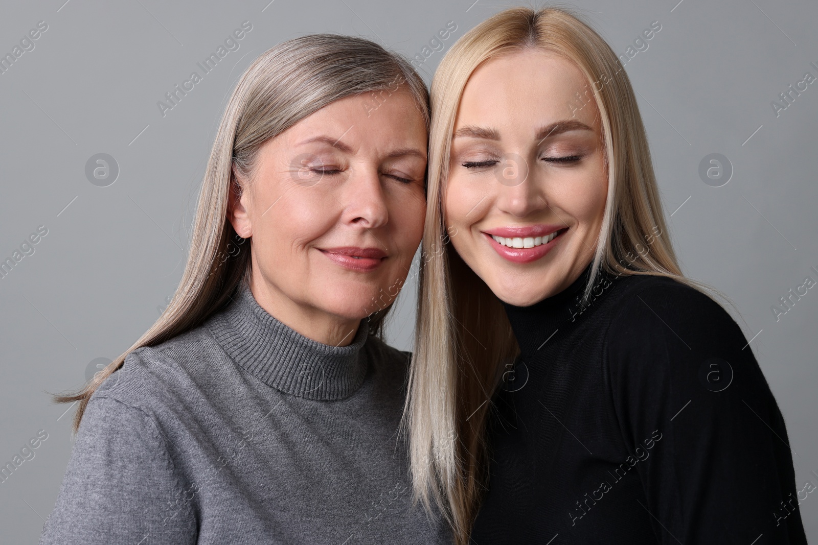 Photo of Family portrait of young woman and her mother on grey background