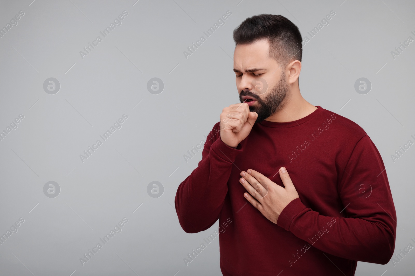 Photo of Sick man coughing on gray background, space for text