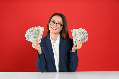 Photo of Young woman with money at table on crimson background