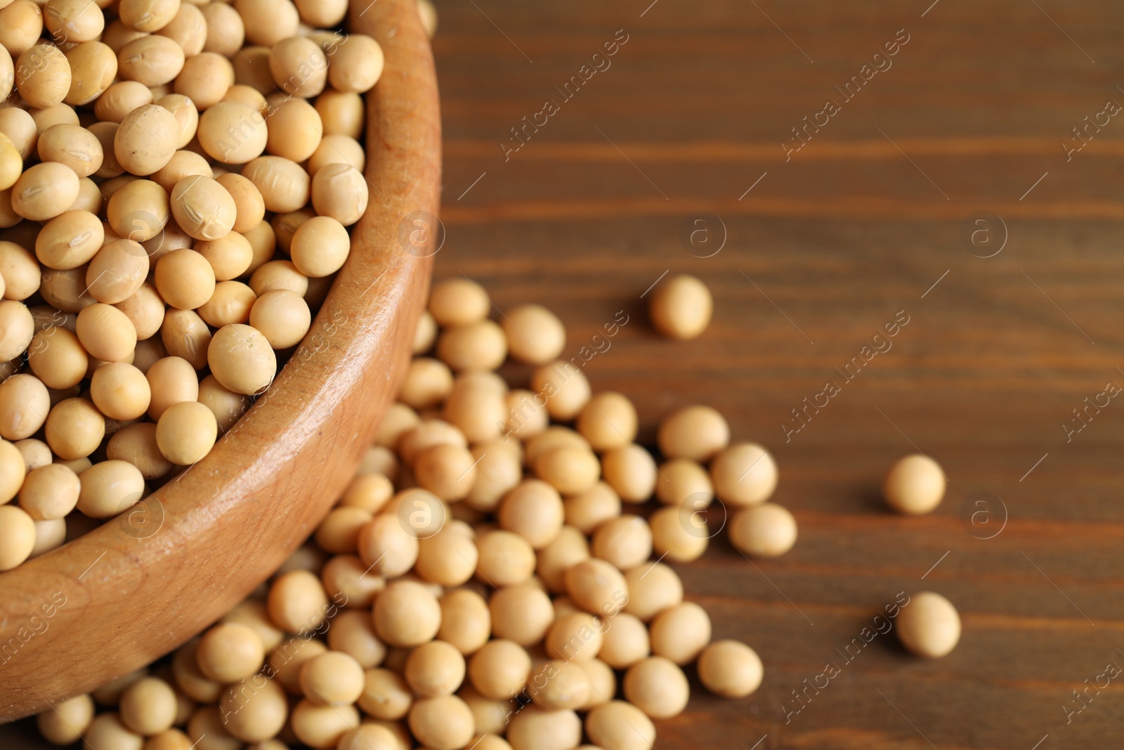 Photo of Bowl with soy on wooden table, closeup. Space for text