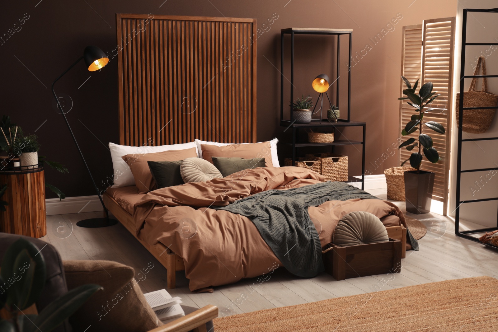 Photo of Stylish room interior with large bed near brown wall