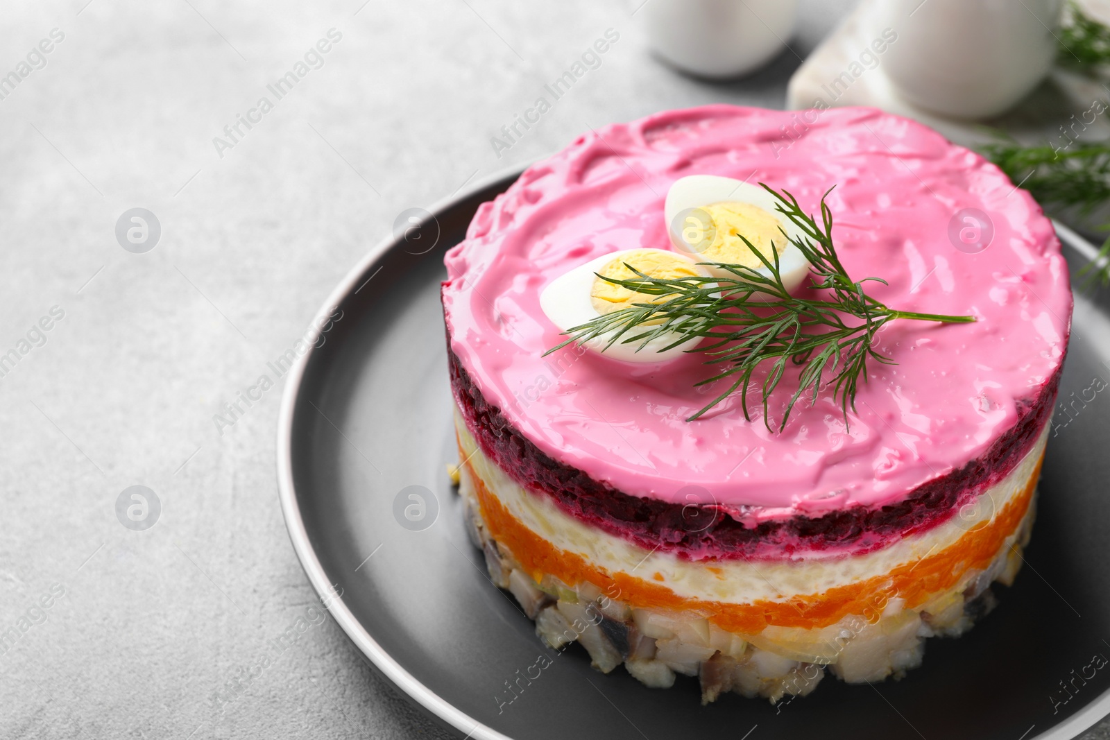 Photo of Herring under fur coat salad on light grey table, space for text. Traditional Russian dish