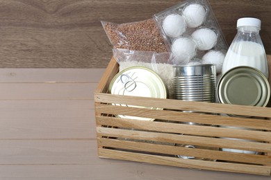 Donation box with food products on wooden table, space for text