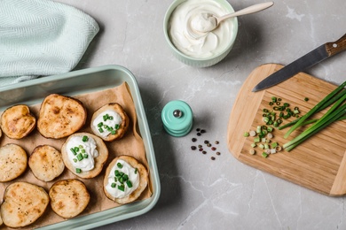 Photo of Sour cream dressing and delicious potato wedges on light grey table, flat lay