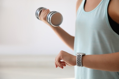 Photo of Woman checking fitness tracker indoors, closeup view
