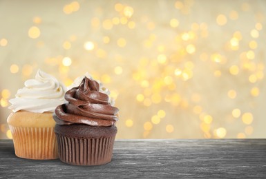 Image of Yummy birthday cupcakes on grey table against blurred lights. Space for text