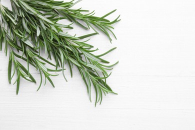 Photo of Fresh green rosemary twigs on white wooden table, top view. Space for text