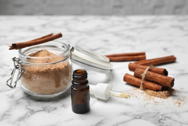 Photo of Bottle with cinnamon oil, powder and sticks on light table