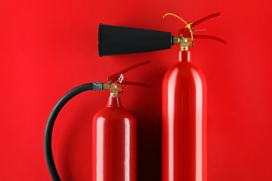 Photo of Fire extinguishers on red background, flat lay