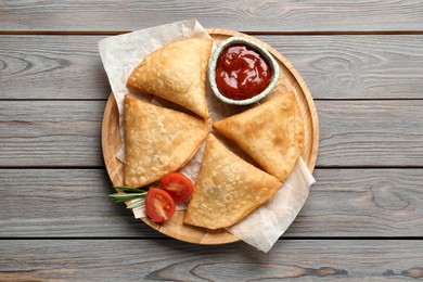 Fresh delicious crispy samosas served on wooden table, top view