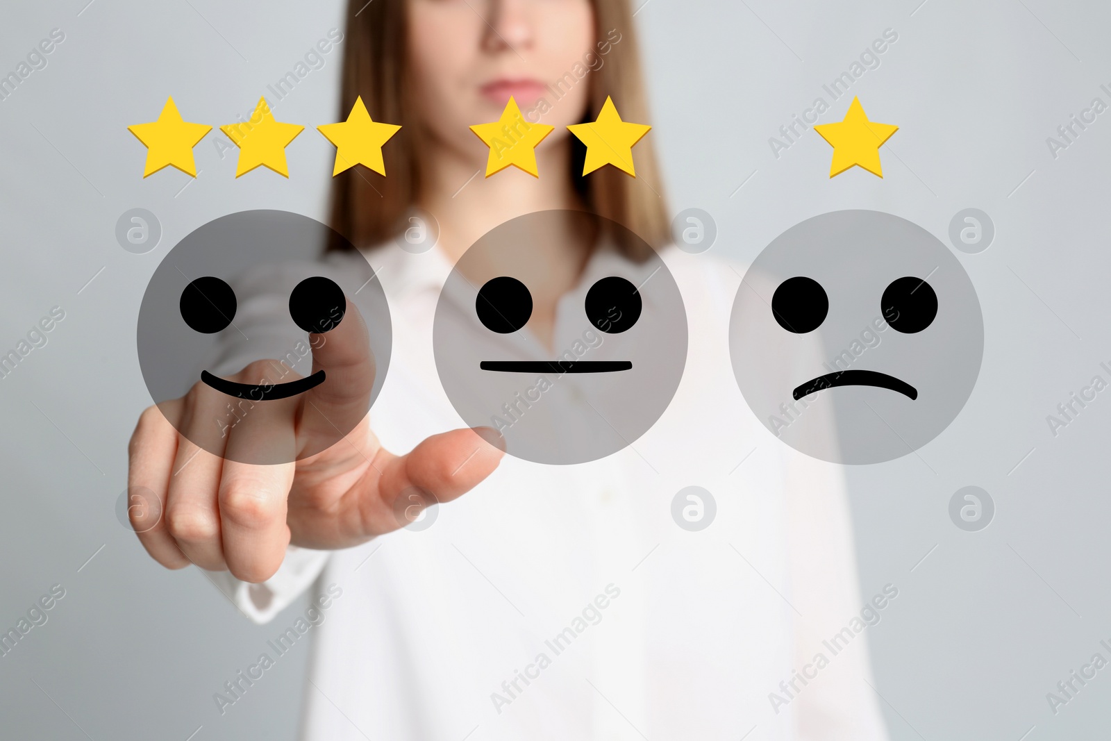 Image of Woman pointing at virtual emoticon to give feedback on light grey, closeup