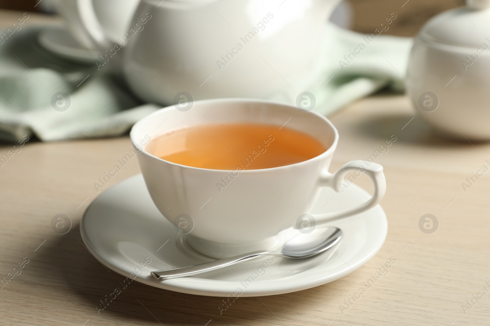 Photo of Cup of hot green tea on wooden table