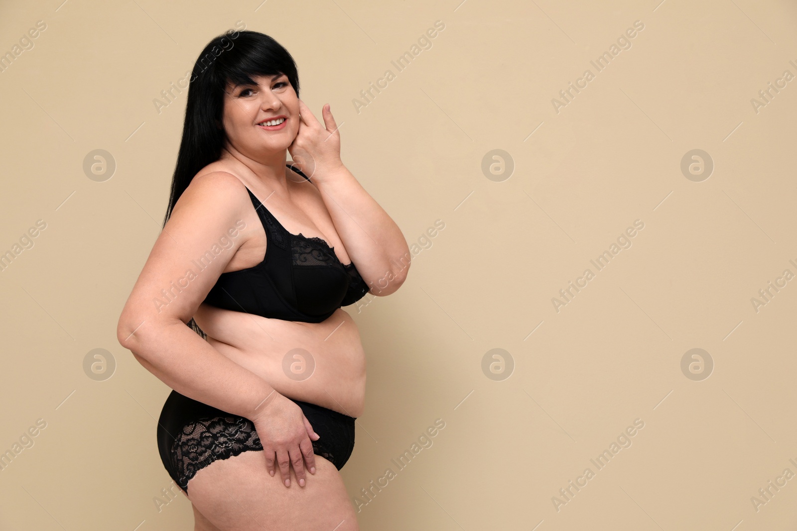 Photo of Beautiful overweight woman in black underwear on beige background, space for text. Plus-size model
