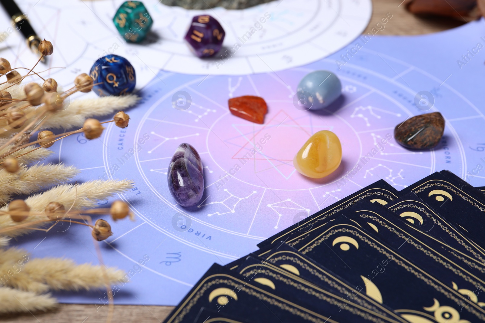 Photo of Zodiac wheel, tarot cards, astrology dices and gemstones on table, selective focus