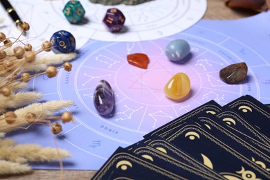 Zodiac wheel, tarot cards, astrology dices and gemstones on table, selective focus