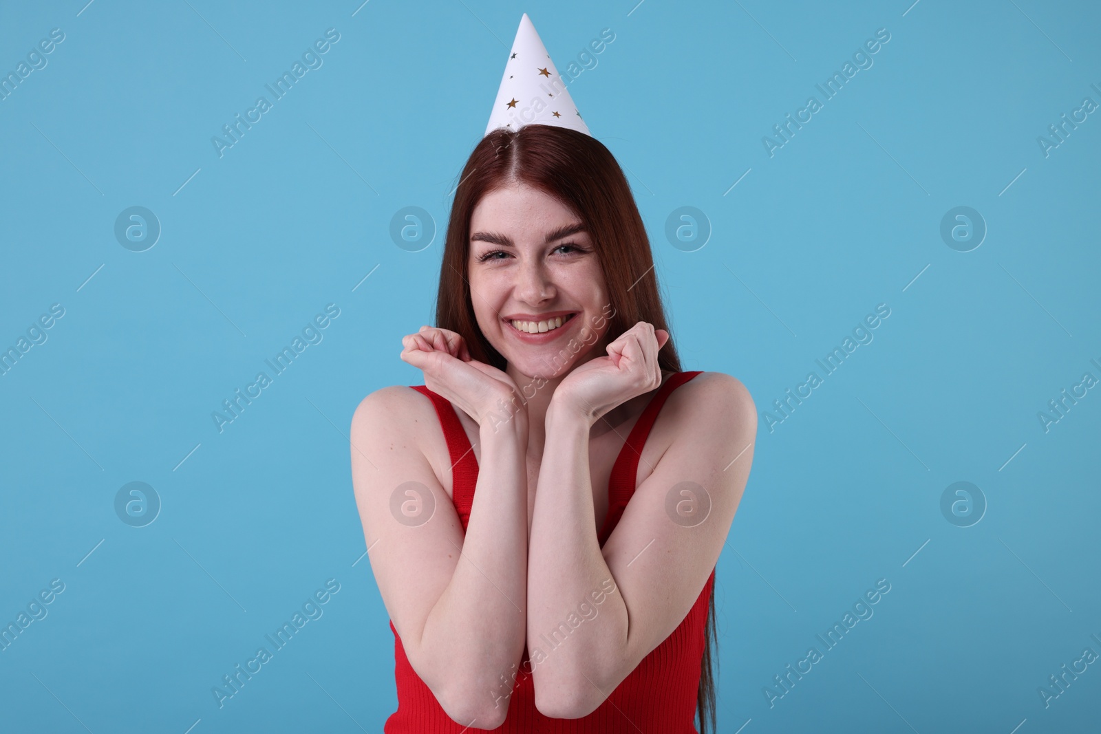 Photo of Happy woman in party hat on light blue background