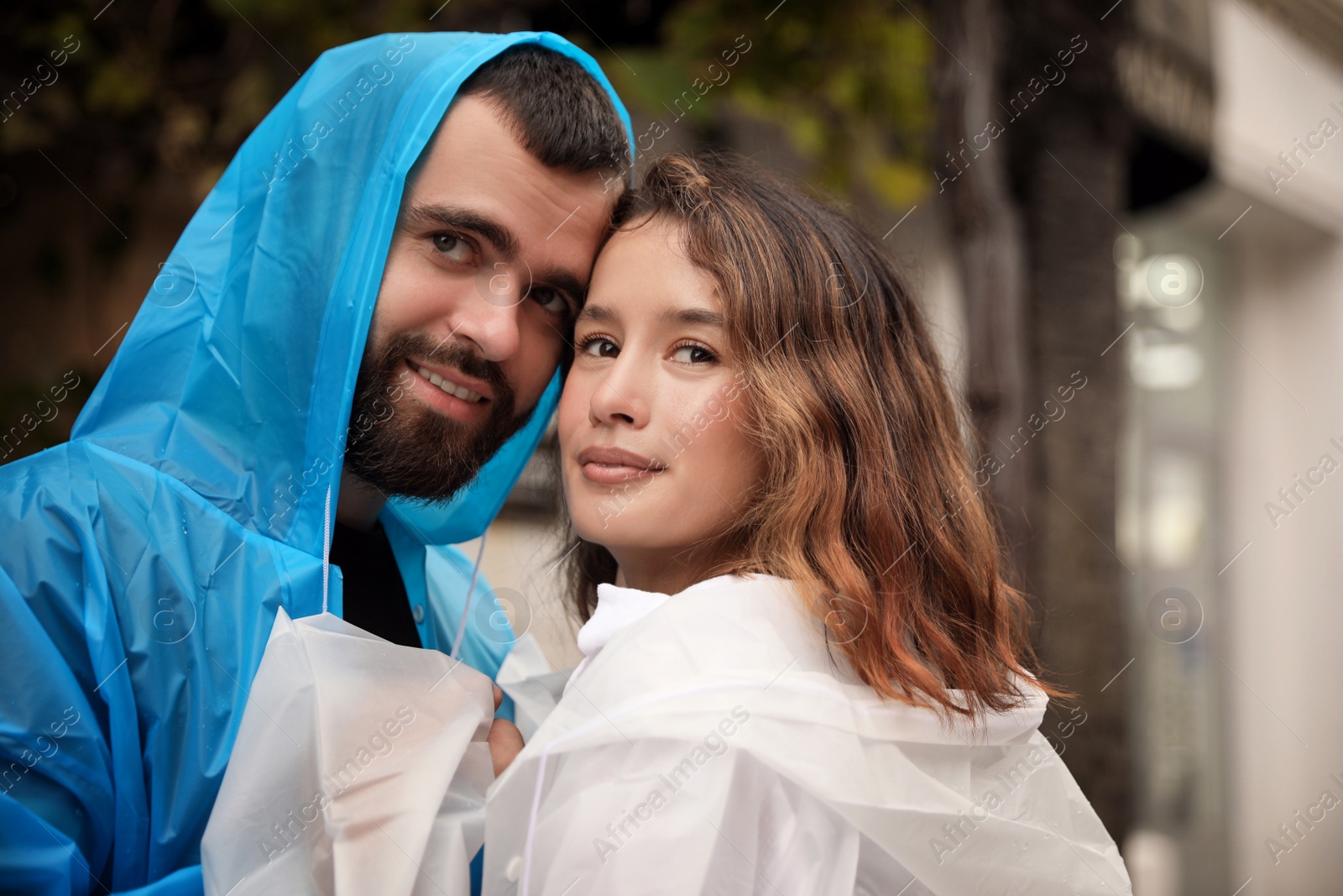 Photo of Young couple in raincoats enjoying time together on city street