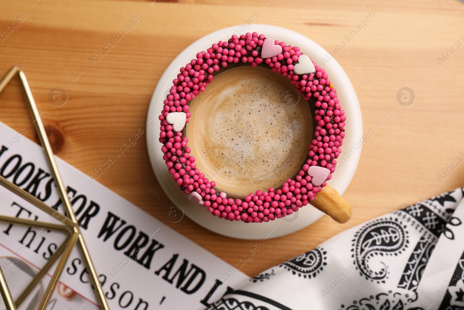 Photo of Flat lay composition with delicious edible biscuit cup of coffee decorated with sprinkles on wooden table