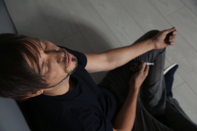 Photo of Male drug addict with syringe sitting on floor, above view