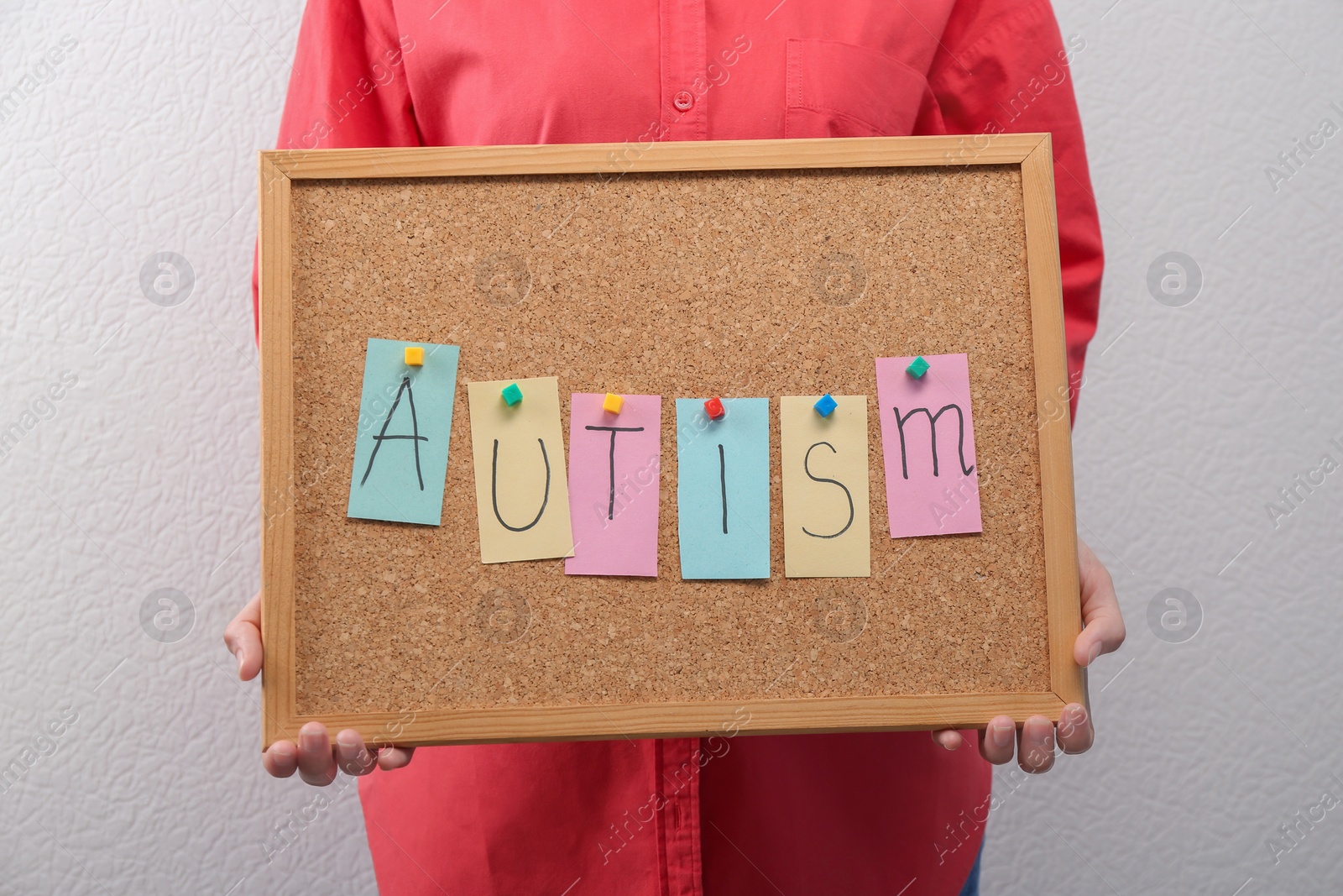 Photo of Woman holding board with word "Autism" on light background