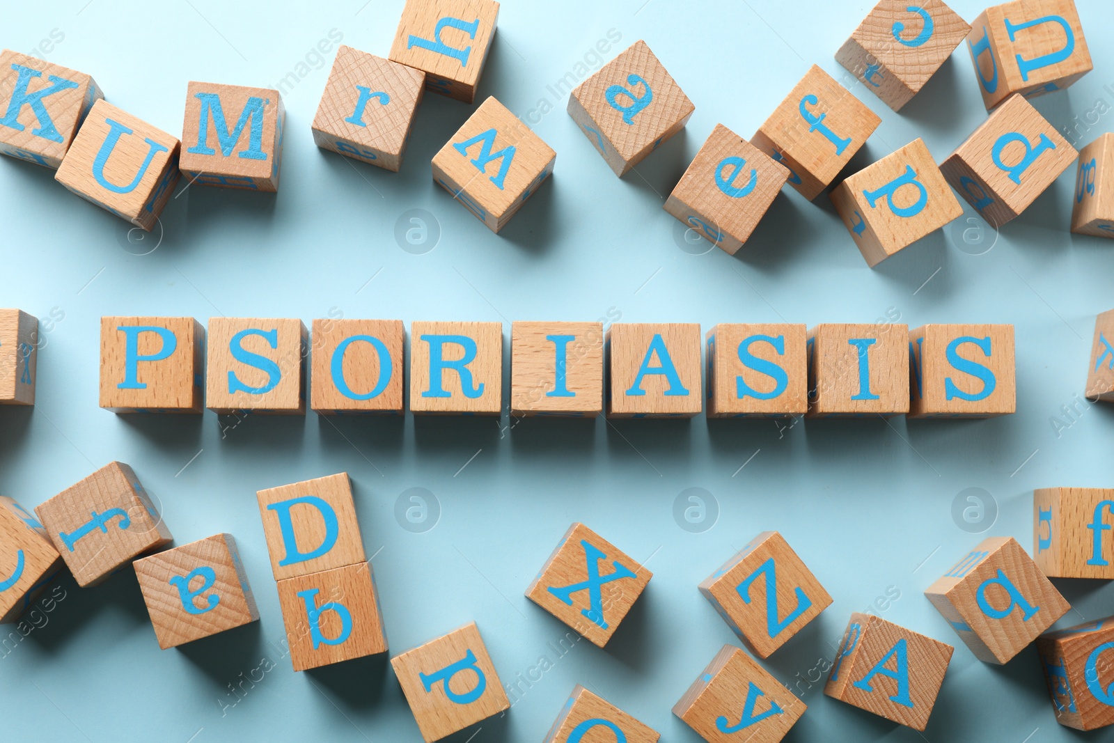 Photo of Word Psoriasis made of wooden cubes with letters on light blue background, flat lay