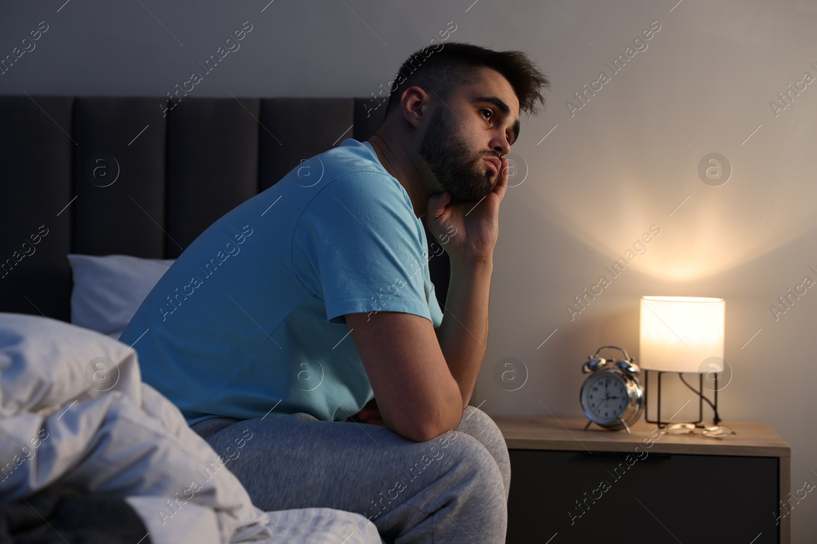 Photo of Frustrated man suffering from insomnia on bed