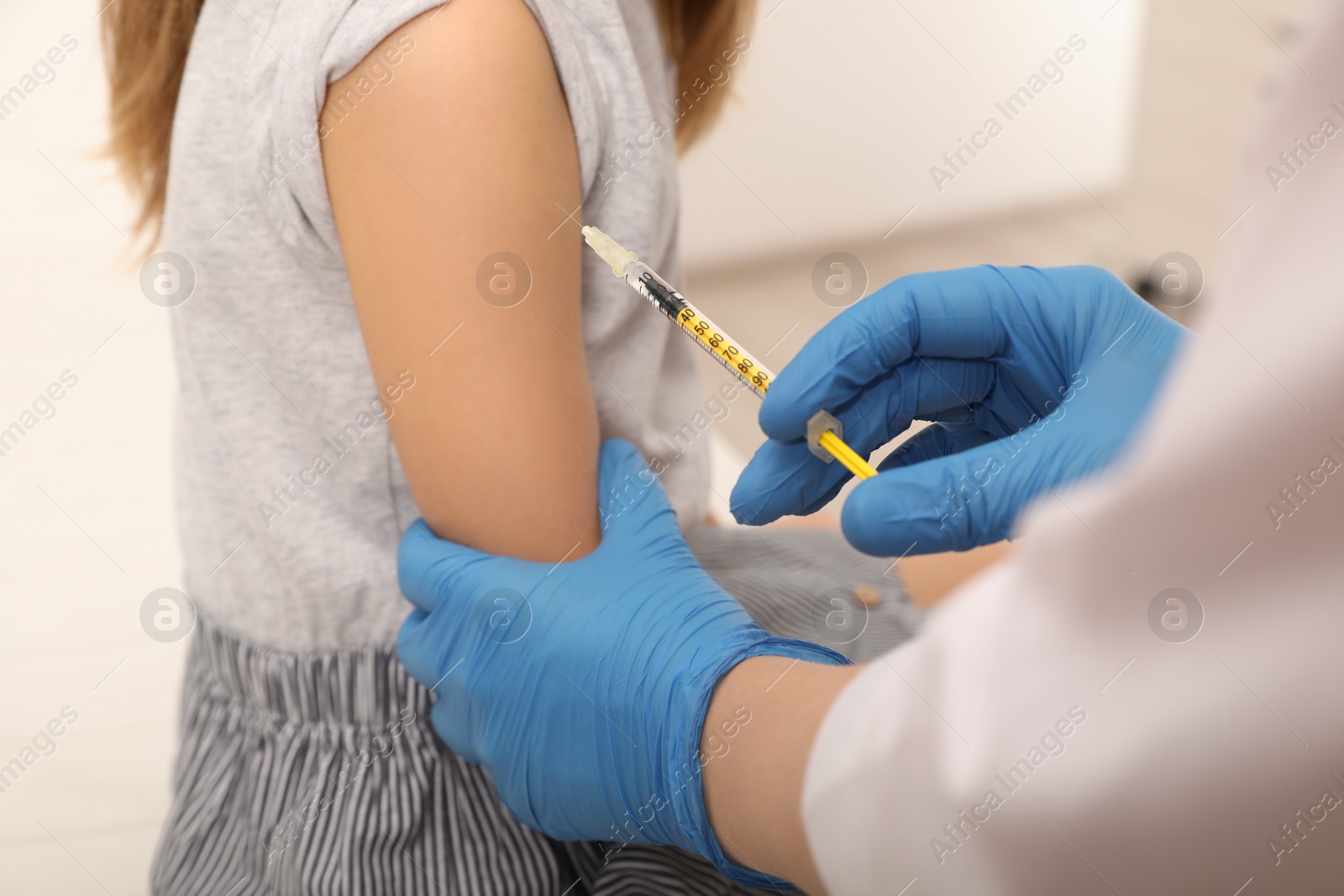Photo of Doctor giving injection to little girl in hospital, closeup. Immunization concept