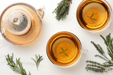 Aromatic herbal tea with thyme and rosemary on white marble table, flat lay