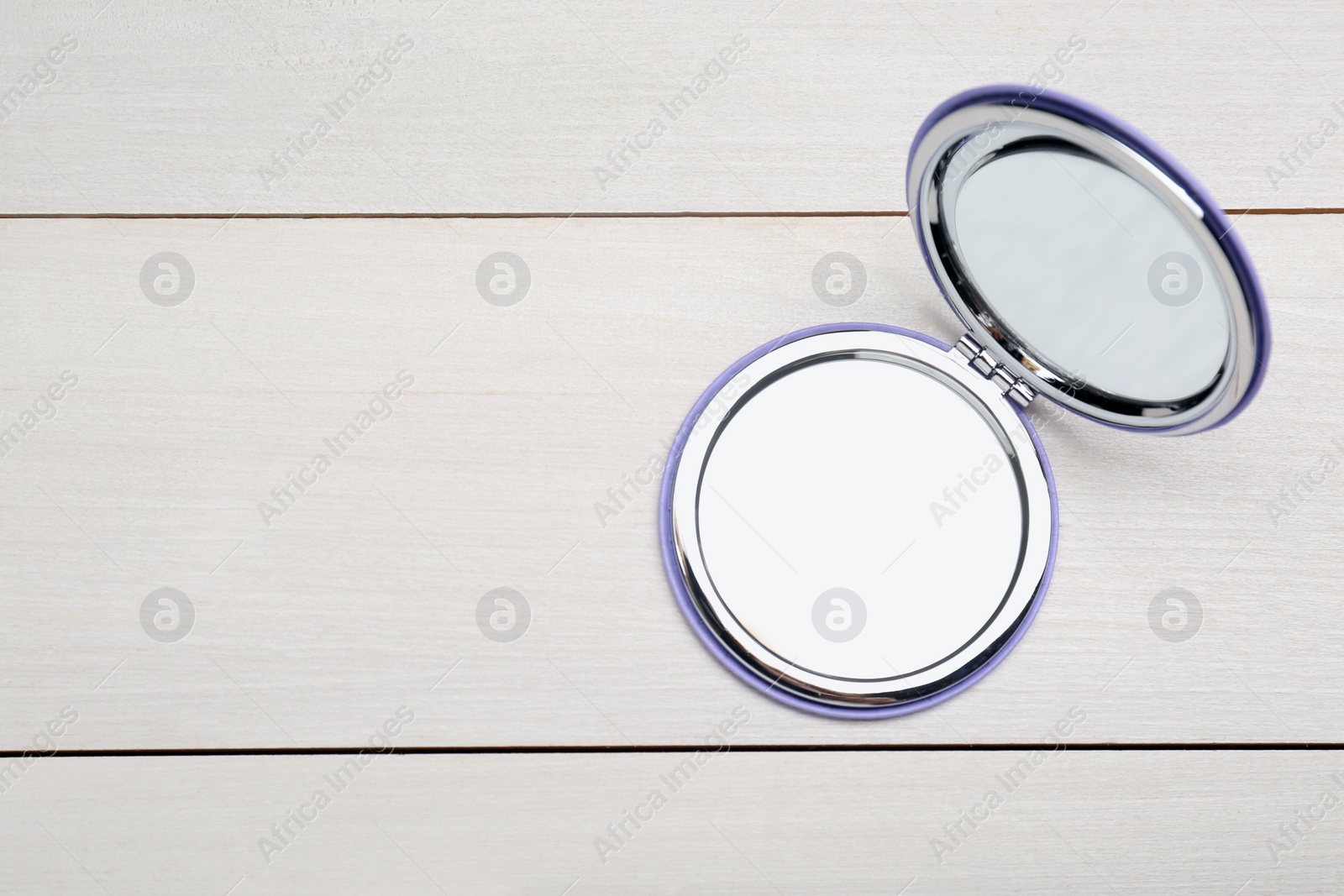 Photo of Stylish cosmetic pocket mirror on white wooden table, top view. Space for text