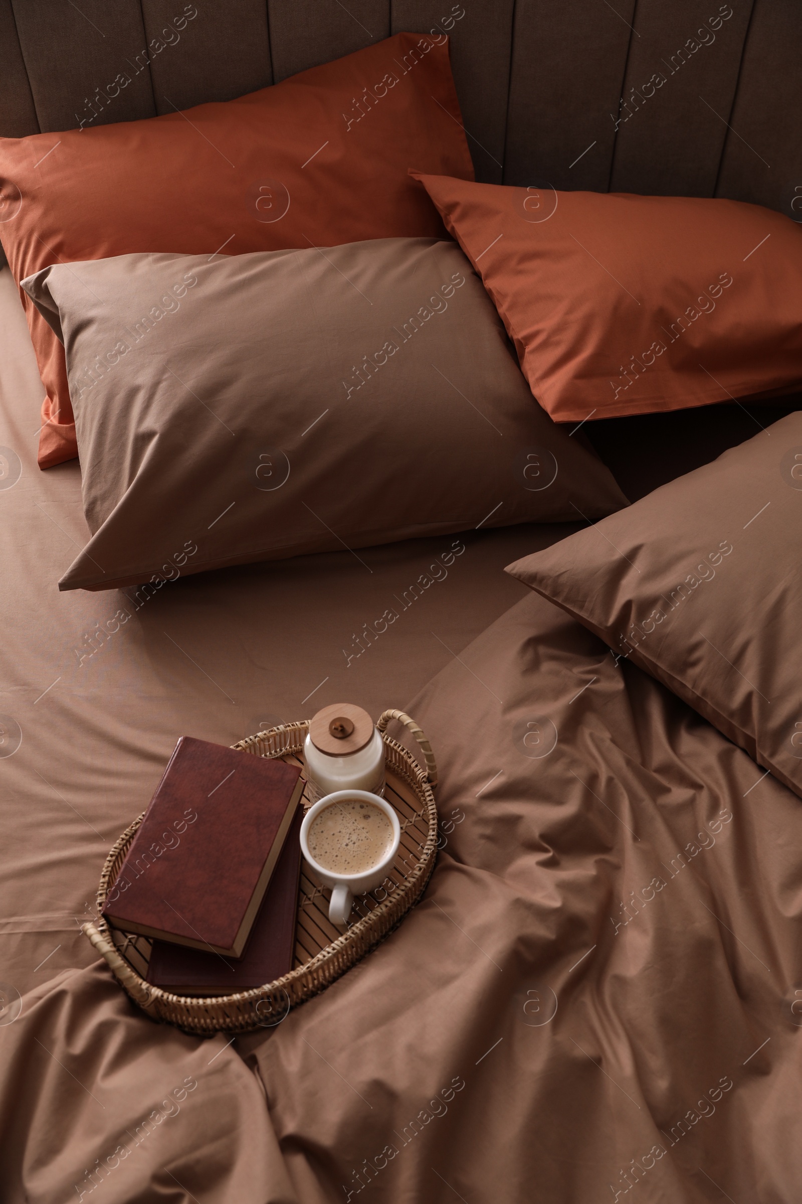Photo of Cup of hot coffee and books on bed with stylish linens, above view
