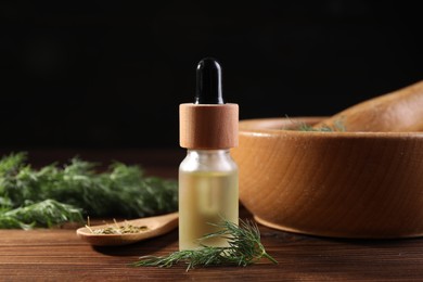 Bottle of essential oil and fresh dill on wooden table