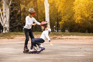 Happy children roller skating in autumn park