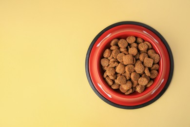 Photo of Dry dog food in feeding bowl on beige background, top view. Space for text