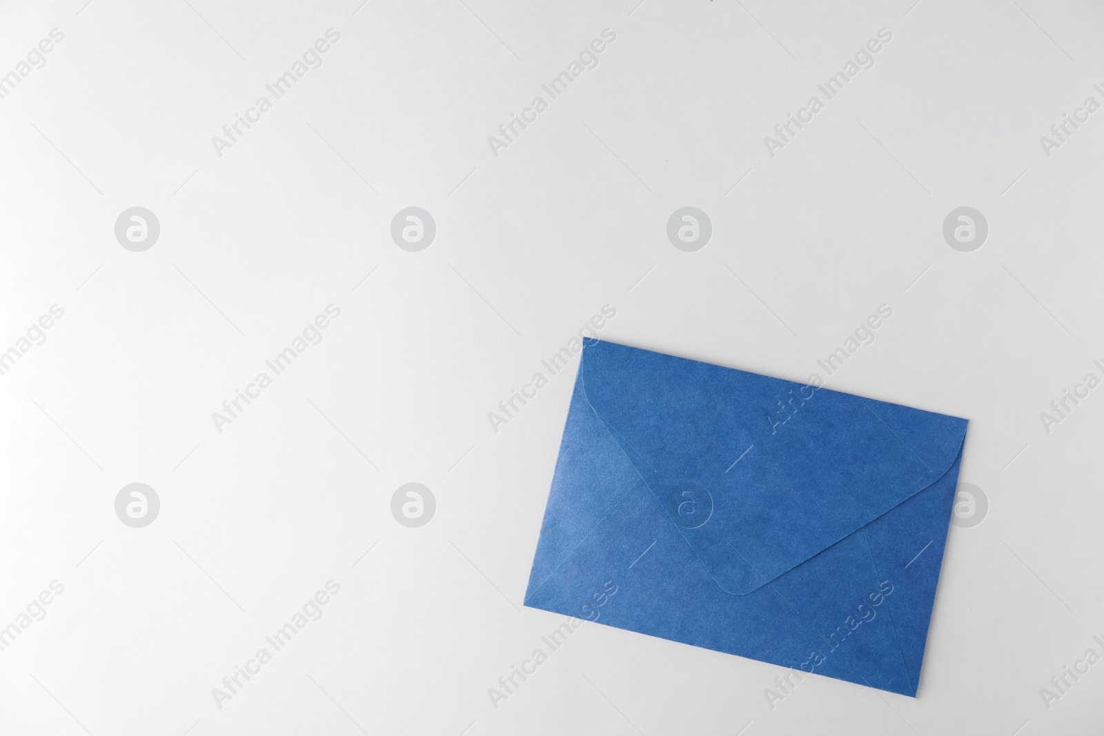 Photo of Blue paper envelope on light background, top view. Space for text